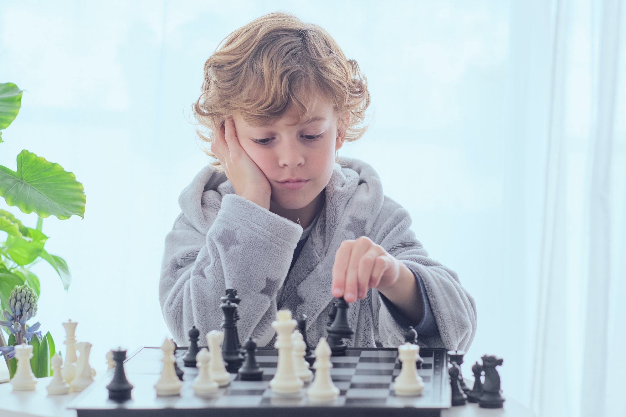Clever boy playing chess in room